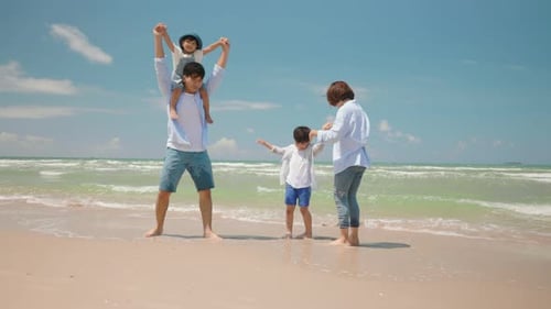 Asian father and mother play with child at the beach on the summer day