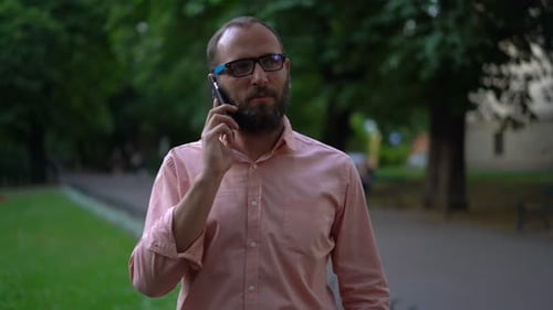 Handsome Man Talking on Cellphone in City Park 30s