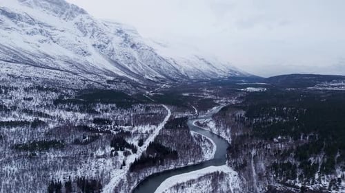 Drohnenaufnahme der schneebedeckten Berge und des gewundenen Flusses Norwegens, der die natürliche Schönheit zeigt