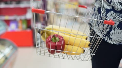 Woman choosing fresh fruits and vegetables in a colorful supermarket grocery shop