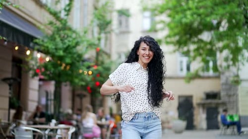 Happy young woman dancing on the city street. Cheerful Curly Attractive Pretty Female dancer