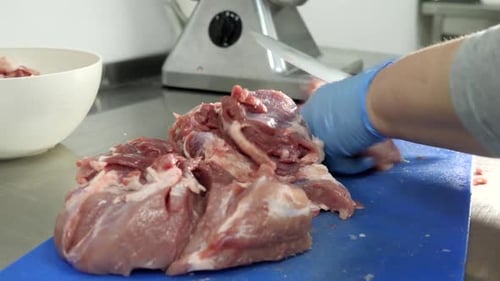 Hands Cutting Raw Pork for Grinding
