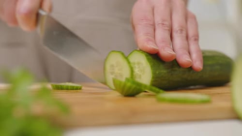 Cucumber Slicing with Knife on Wooden Board