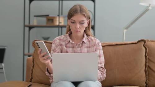 Woman Uses Laptop and Phone While Sitting