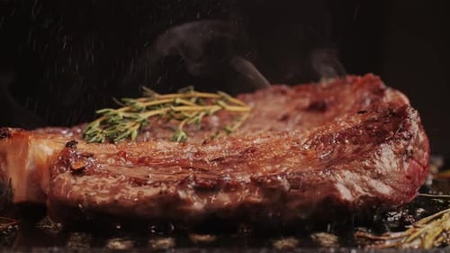 Fresh Marbled Beef with Pepper Salt and Rosemary Closeup Macro Cooking Juicy Steak on Grill with Oil