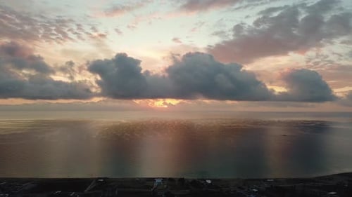 Amazing sunset in orange sky with soft clouds over the water.