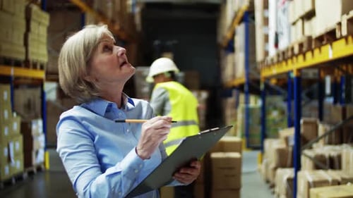 Senior Woman Manager and Man Worker Working in a Warehouse