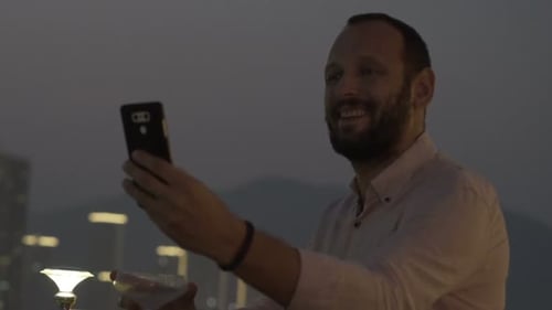 Young Man with Drink Taking Selfie with Cellphone on Terrace in Bar