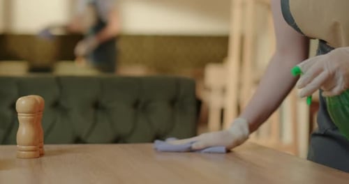 Crop Waitress Disinfecting Table in Cafeteria