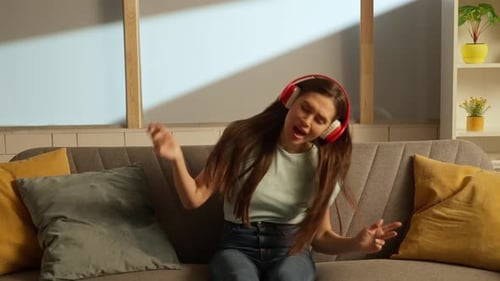 Woman with Headphones Dancing on Sofa Indoors
