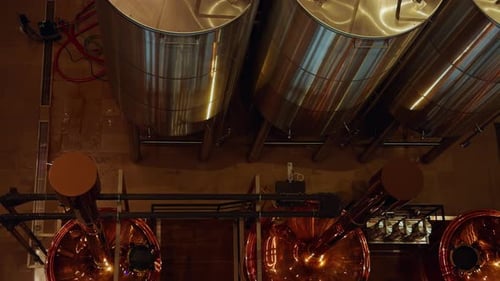 Fermentationstanks aus glänzendem Stahl von oben mit nassem Boden und angeschlossenen Schläuchen in Ba Na Hills