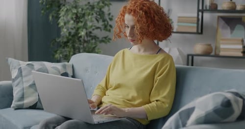 Woman Using Laptop Computer on Couch at Home