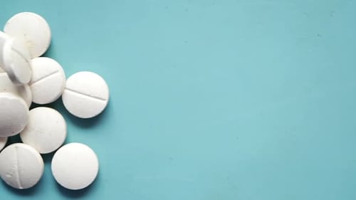 Pile of White Pills on Blue Background