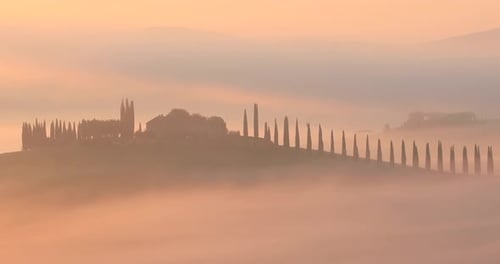 Beautiful mist surrounds a farmhouse at sunrise in the Val d'Orcia of Tuscany, Italy.