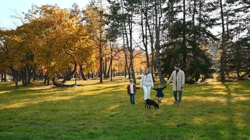 Happy family in an autumn park. Mother and father walking with daughter, son and their dog, yellowed