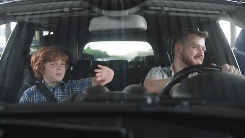 Glücklicher Vater und sein Sohn sitzen im Auto und winken mit den Händen in Zeitlupe