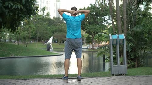 Young man stretching arms after jogging workout in the city park