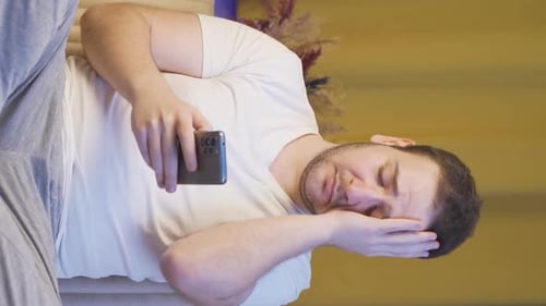 Frustrated Man Looking at Phone on Sofa