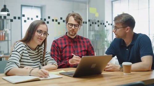 Three colleagues collaborate at an office desk