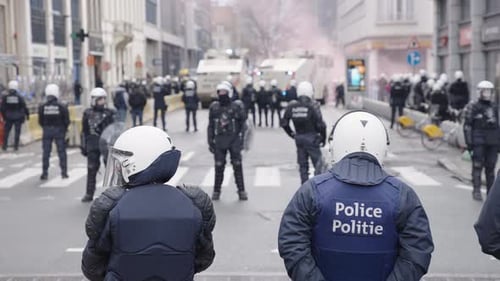 Belgian police line both sides of the street in full riot gear during protest, slow motion