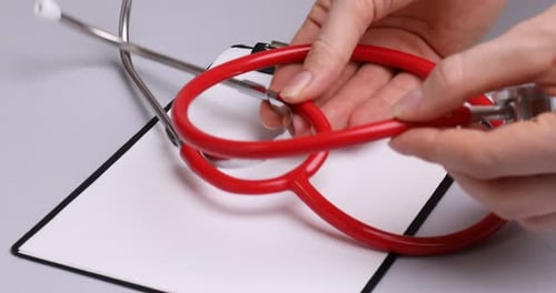 Red Stethoscope Placed on Clipboard in Medical Setting