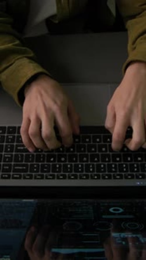 Vertical of Young Male Programmer Typing on Laptop in Office in Evening