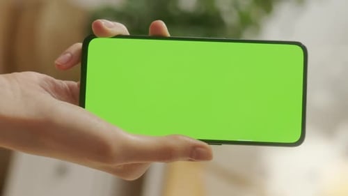 Point of View of Young Woman at Home Sitting on Living Room Using With Green Mockup Screen