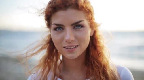 Happy young redhead woman laughing on a beautiful beach experiencing joy