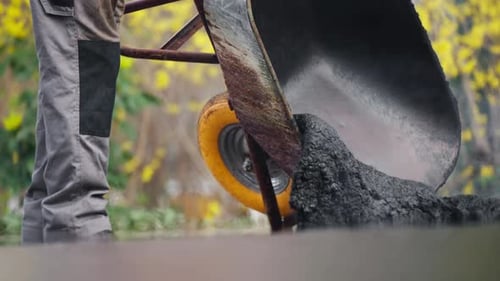 Asphalt pouring out of wheelbarrow for street repair