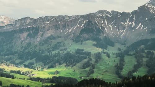 Majestic Alpine Landscape with Snow-Capped Peaks and Lush Green Valleys