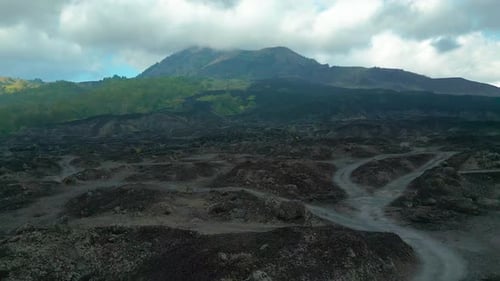 Aerial View of Mount Batur's Rugged Landscape Featuring Black Lava Fields and Vegetation Showcasing