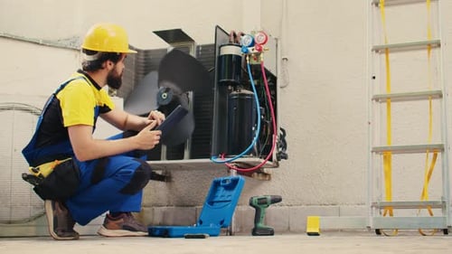 Air Conditioning Technician Repairs Unit Using Tablet