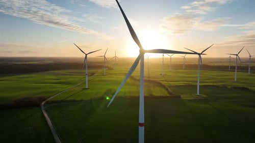 Aerial footage wind turbine spin momentarily concealing the sun