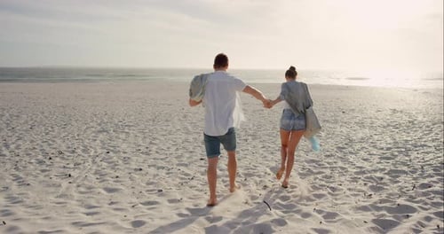 4k video footage of a young couple walking on the beach at sunset