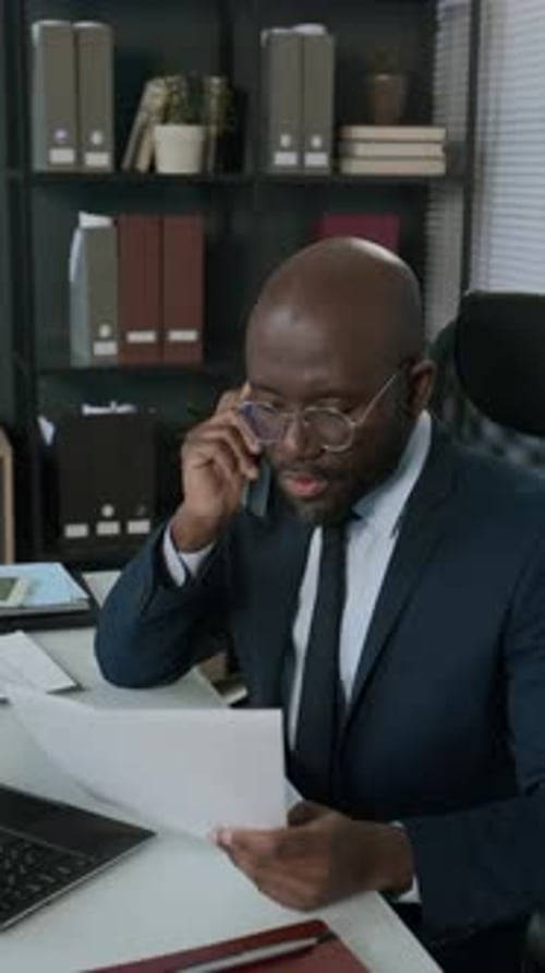 Financial Advisor Reading Document and Talking on Phone at Office Workplace