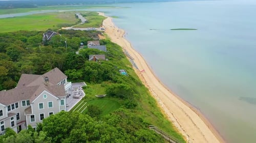Cape Cod shoreline panorama with oceanfront houses and boat offshore during dramatic high tide