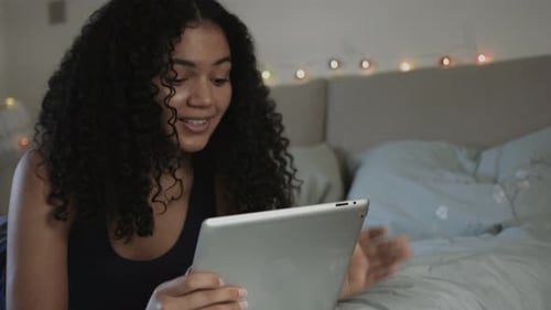 Woman Lies in Bed Using a Tablet