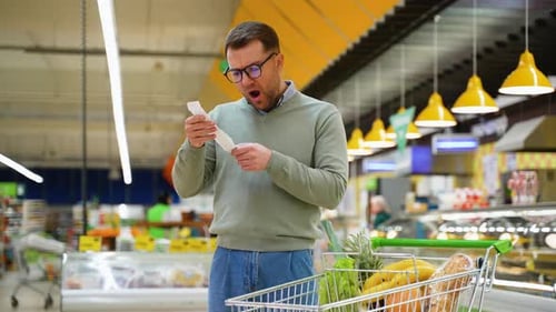 Shocked Man Reacting to High Grocery Bill in Supermarket
