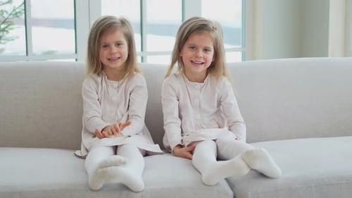 Twin Girls Smiling on a Couch