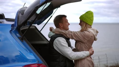 A Romantic Couple Embracing Tenderly By the Beach While Sitting in a Blue Car Under the Sun