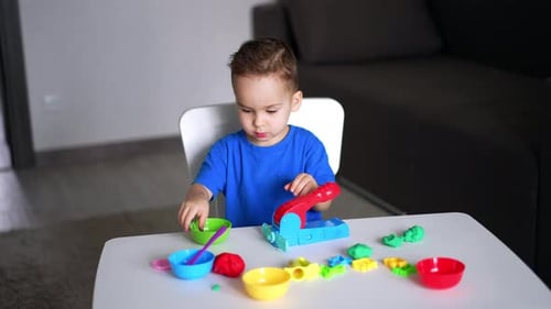 Child Plays With Clay at Table