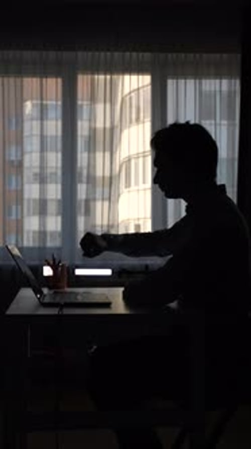 Vertical Video Businessman Checking Time While Working on Laptop in Dark Office Room
