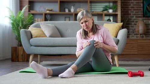 Senior Woman Experiences Knee Pain During Home Workout