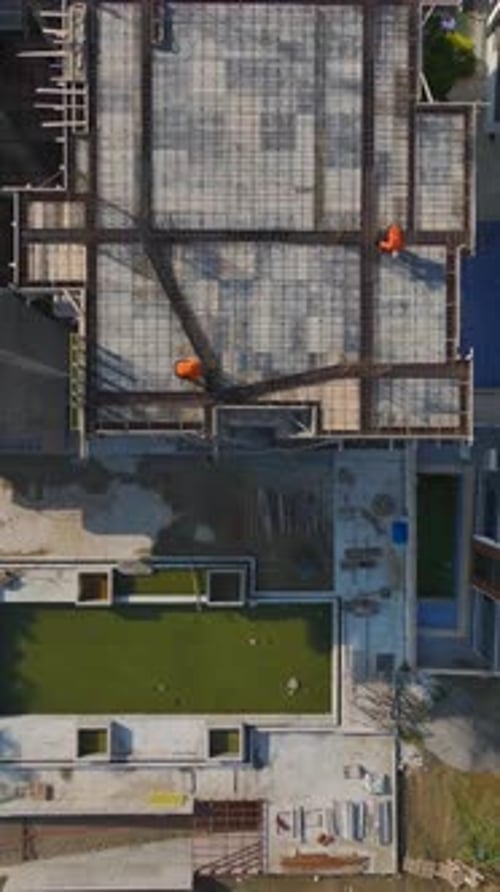 Vídeo vertical: perspectiva aérea de equipos que utilizan estructuras metálicas y herramientas para construir paredes estructurales