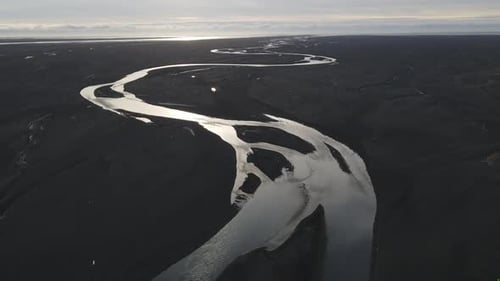 Vista aérea del sinuoso río a través de un paisaje oscuro, Islandia.