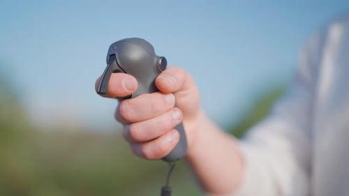 Male use rc motion control to fly fpv drone, blurry nature background