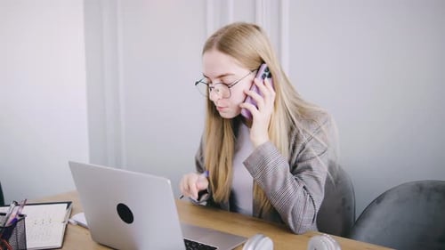 Woman Using Laptop and Talking on Phone