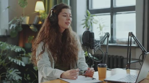 Pretty Female Blogger Making Audio Podcast or Live Streaming in Studio