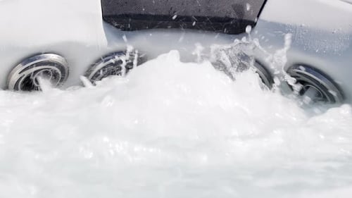 Static, slow motion shot of the jets of a jacuzzi being turned on, causing the bubbles to froth and