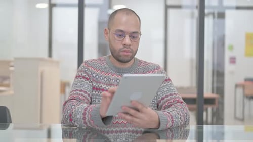Young Adult Using Tablet at Glass Table in Office